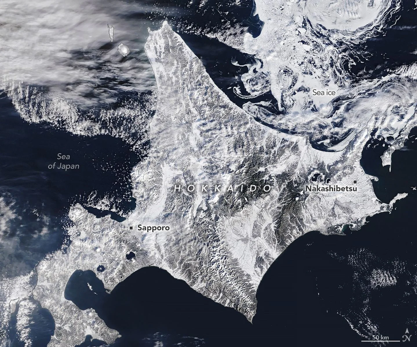A satellite image shows snow blanketing Hokkaido, Japan, with sea ice swirling just north of the island.